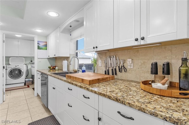 kitchen with washing machine and dryer, sink, white cabinets, and light stone counters