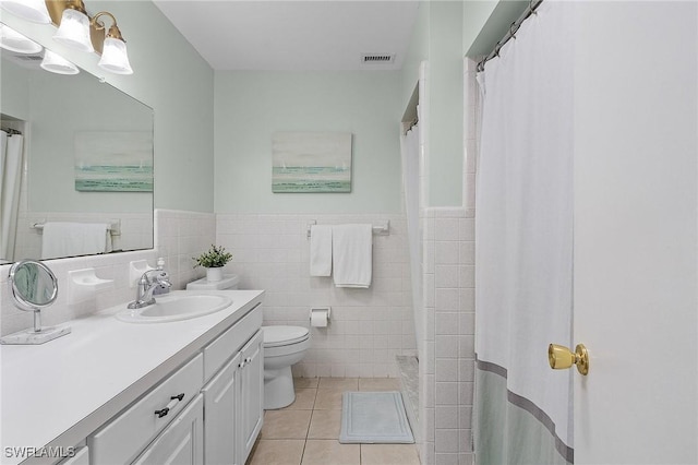 bathroom featuring curtained shower, tile walls, tile patterned flooring, vanity, and toilet