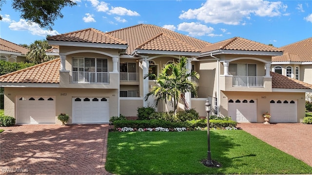 mediterranean / spanish-style home featuring a front lawn and a balcony