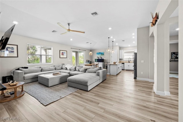 living room featuring light wood-type flooring and ceiling fan