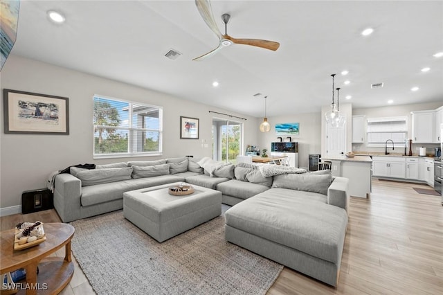 living room featuring sink, ceiling fan, and light wood-type flooring