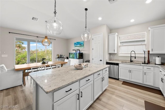 kitchen with white cabinets, hanging light fixtures, and stainless steel dishwasher