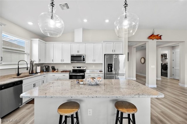 kitchen featuring appliances with stainless steel finishes, sink, hanging light fixtures, and white cabinets