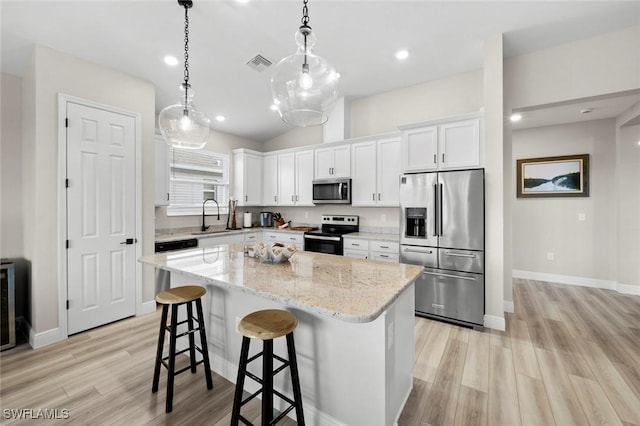 kitchen with sink, a kitchen island, decorative light fixtures, stainless steel appliances, and white cabinets