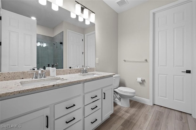 bathroom featuring toilet, wood-type flooring, vanity, and a shower with door