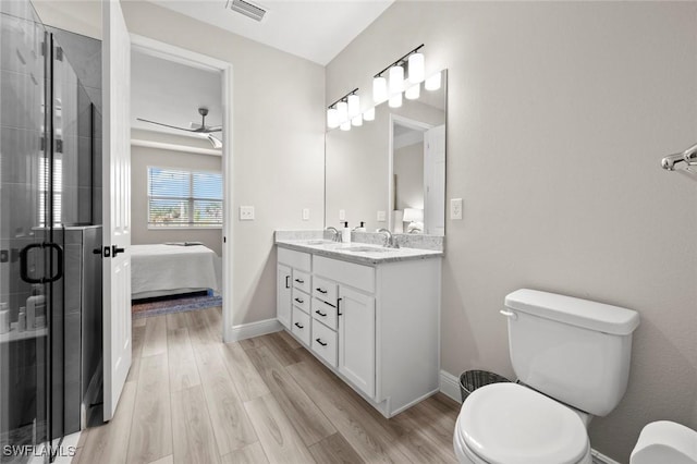 bathroom with hardwood / wood-style flooring, a shower with shower door, toilet, ceiling fan, and vanity