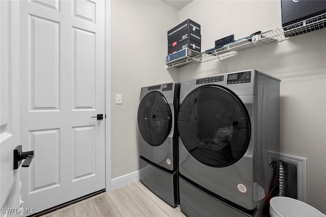 clothes washing area featuring light hardwood / wood-style flooring and separate washer and dryer