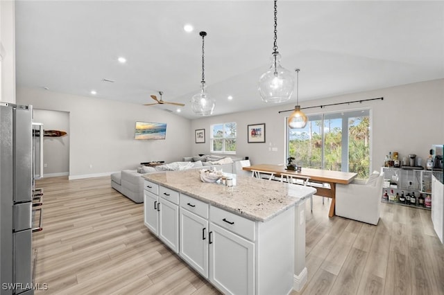 kitchen with white cabinetry, light wood-type flooring, lofted ceiling, hanging light fixtures, and a center island