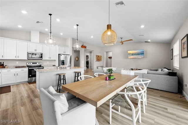 dining room with light hardwood / wood-style flooring and vaulted ceiling