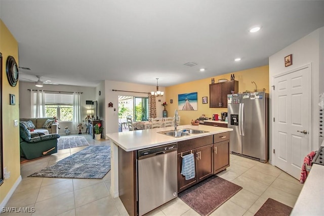 kitchen featuring pendant lighting, stainless steel appliances, light countertops, a kitchen island with sink, and a sink