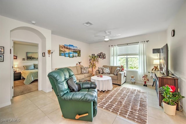 living room with ceiling fan, light tile patterned floors, arched walkways, visible vents, and baseboards