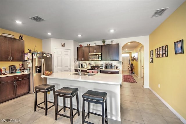 kitchen with stainless steel appliances, a kitchen island with sink, light countertops, and a sink