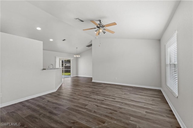 empty room with ceiling fan with notable chandelier, visible vents, baseboards, vaulted ceiling, and dark wood finished floors