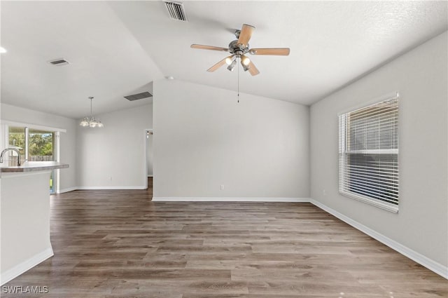 spare room with lofted ceiling, ceiling fan with notable chandelier, wood finished floors, and visible vents