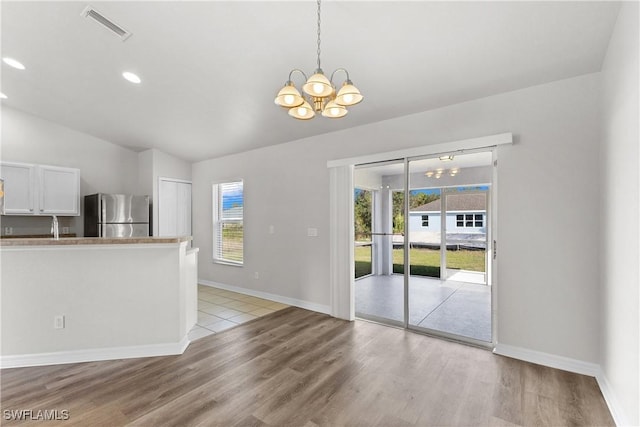 kitchen with a notable chandelier, visible vents, hanging light fixtures, freestanding refrigerator, and white cabinetry