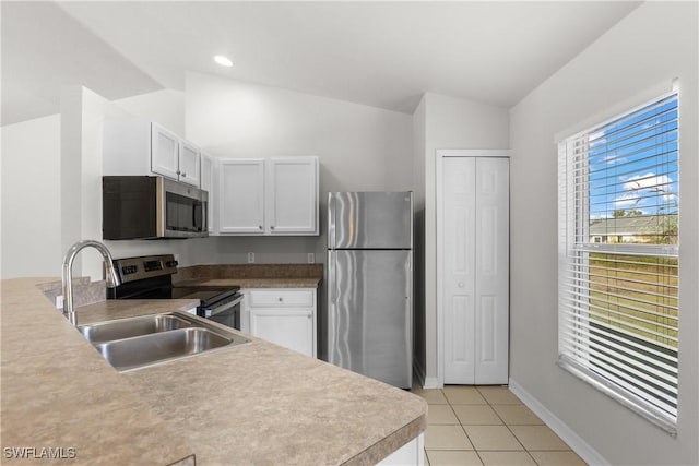 kitchen with light tile patterned floors, stainless steel appliances, a sink, and white cabinetry