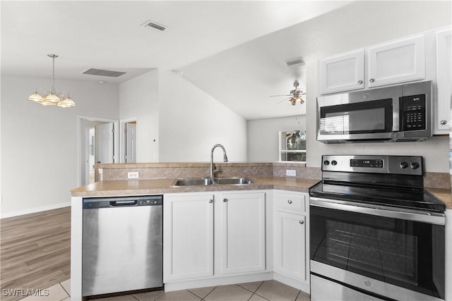 kitchen featuring ceiling fan with notable chandelier, a sink, white cabinets, vaulted ceiling, and appliances with stainless steel finishes