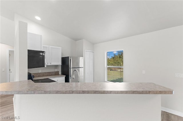 kitchen with light wood-style flooring, electric range, vaulted ceiling, light countertops, and freestanding refrigerator