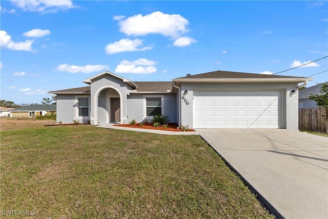 view of front of property with a garage, fence, driveway, stucco siding, and a front yard