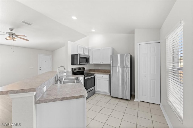 kitchen with stainless steel appliances, a peninsula, a sink, white cabinets, and light countertops