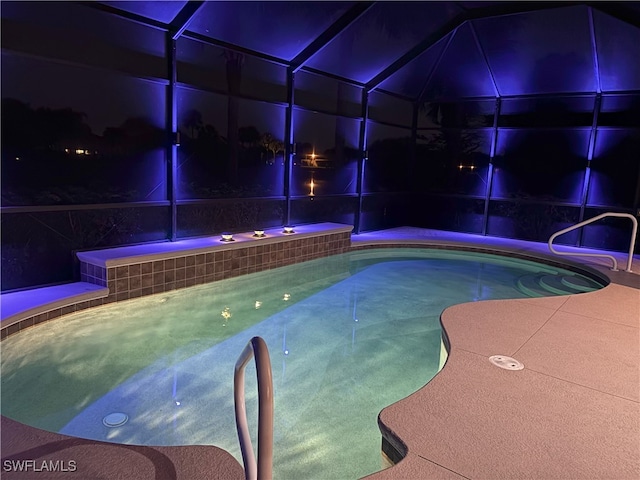 pool at twilight with a lanai and an outdoor pool