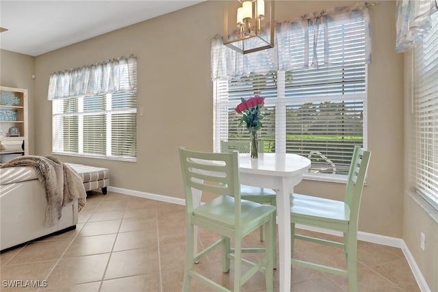 dining space featuring light tile patterned flooring, a notable chandelier, and baseboards