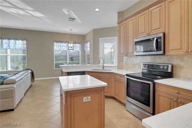 kitchen featuring open floor plan, a center island, stainless steel appliances, light countertops, and a sink