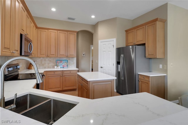 kitchen with a kitchen island, a sink, visible vents, appliances with stainless steel finishes, and backsplash