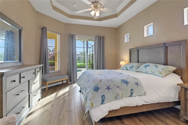 bedroom with access to outside, a ceiling fan, a raised ceiling, and wood finished floors