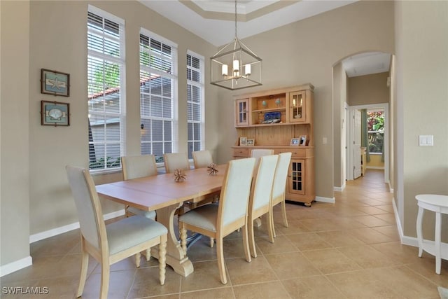 dining area featuring a wealth of natural light, arched walkways, a chandelier, and light tile patterned floors