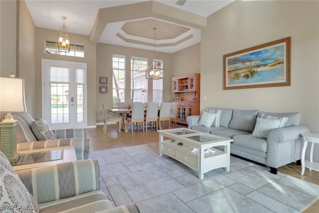 living area featuring a chandelier, a raised ceiling, and baseboards