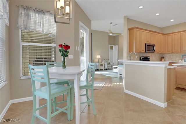 kitchen featuring light countertops, stainless steel microwave, light brown cabinets, and pendant lighting