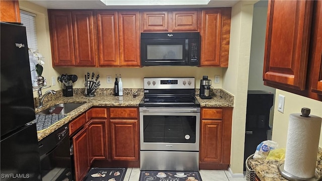 kitchen with light tile patterned flooring, sink, black appliances, and light stone counters