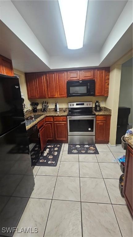 kitchen featuring sink, dark stone countertops, light tile patterned flooring, and black appliances