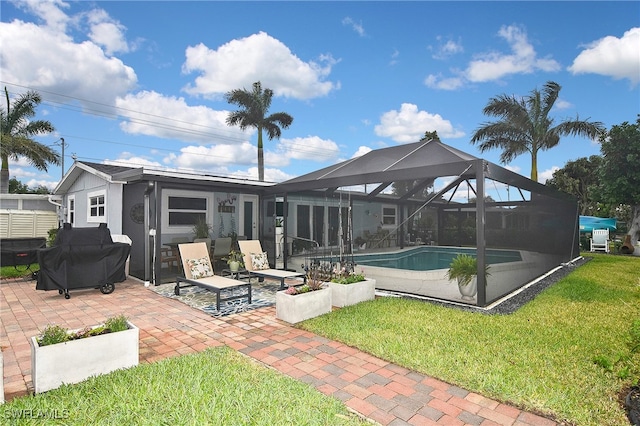 back of property featuring an outdoor pool, glass enclosure, a lawn, and a patio area