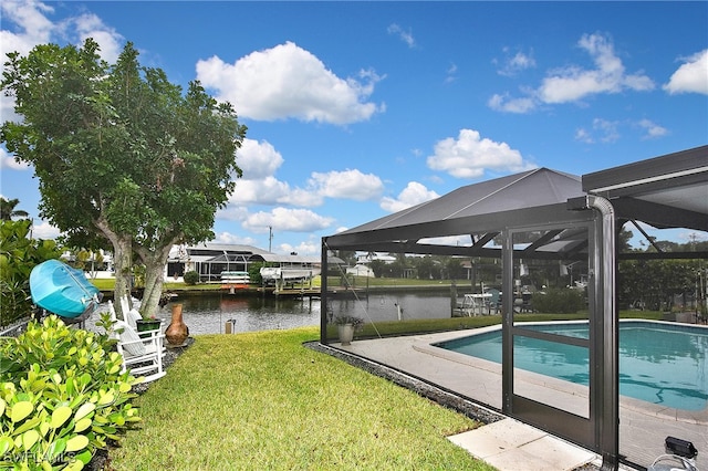 pool with glass enclosure, a lawn, and a water view