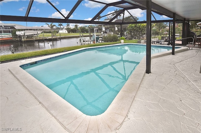 outdoor pool with a patio area, glass enclosure, and a water view