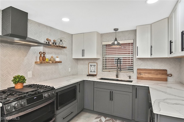 kitchen with gray cabinets, appliances with stainless steel finishes, wall chimney range hood, and a sink