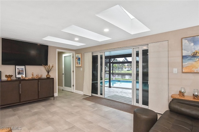 living area with a skylight, recessed lighting, and baseboards