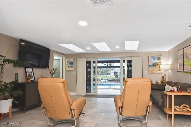 living room with a skylight, recessed lighting, and visible vents