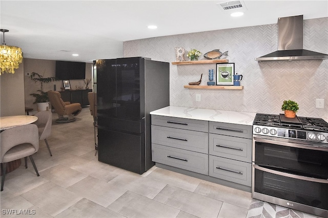 kitchen with visible vents, gray cabinets, light stone counters, double oven range, and wall chimney range hood