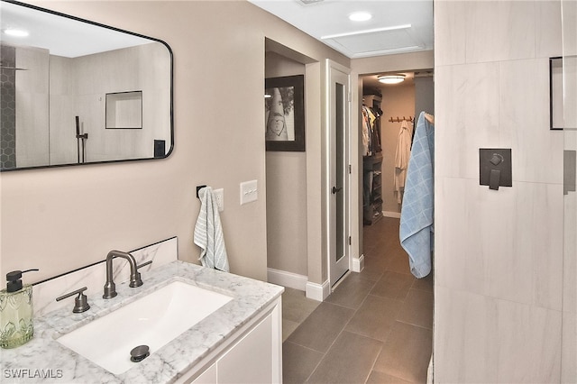 bathroom with tile patterned floors, vanity, a walk in closet, and baseboards