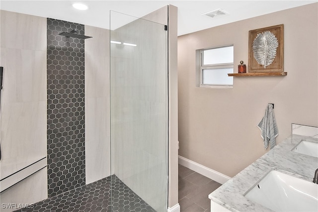 bathroom with visible vents, baseboards, walk in shower, double vanity, and a sink