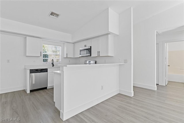 kitchen featuring appliances with stainless steel finishes, kitchen peninsula, sink, and white cabinets