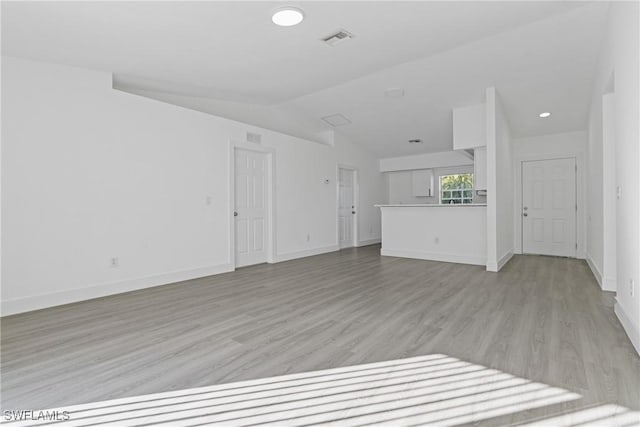 unfurnished living room with vaulted ceiling and light hardwood / wood-style flooring