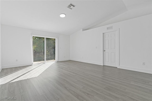 spare room featuring lofted ceiling and hardwood / wood-style floors