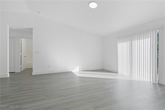 spare room featuring lofted ceiling and hardwood / wood-style floors