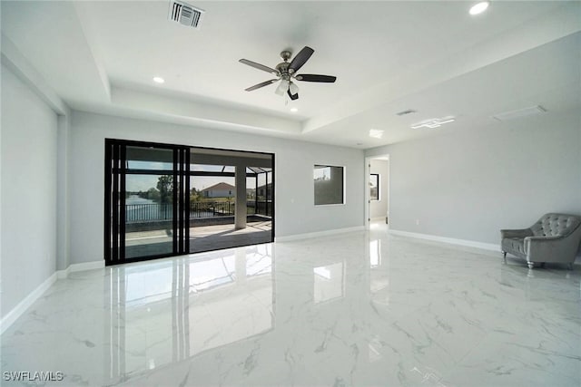 empty room featuring ceiling fan and a raised ceiling