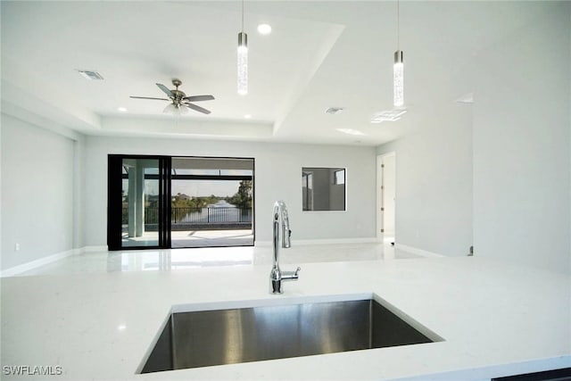 kitchen with sink, decorative light fixtures, and a raised ceiling