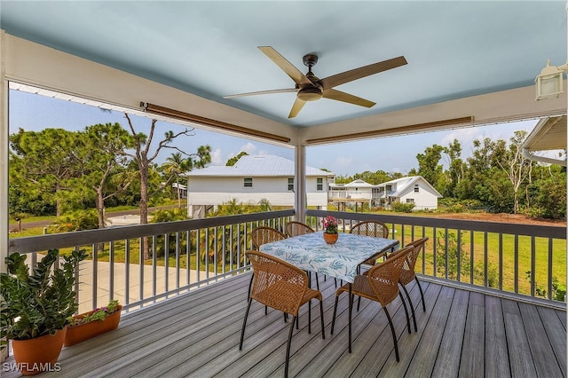 wooden deck with outdoor dining area, a ceiling fan, and a yard